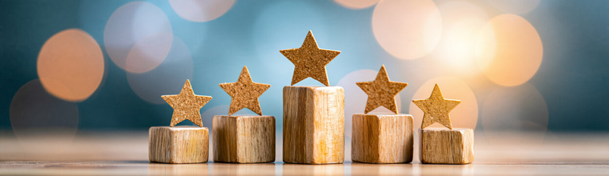 Wooden podiums with sparkling gold stars on top against a blurred background of warm bokeh lights.