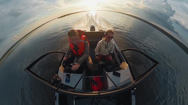 Two fishermen explore the river on the speed motor boat