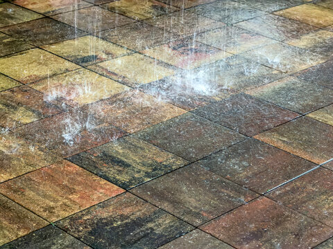 heavy rain falling on wet tiled pavement in urban street. rain in the city.