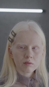 Close-up portrait of attractive albino lady looking at camera indoors in studio with neon light. Individual style and beautiful woman concept.
