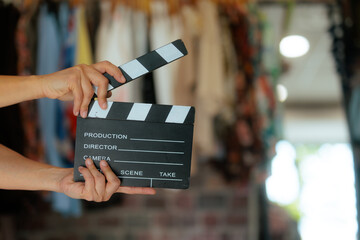 Hands Holding A Movie Clapperboard Inside A Clothing Boutique. Entertainer holds a classic film slate open inside a fashion retail store © nicoletaionescu