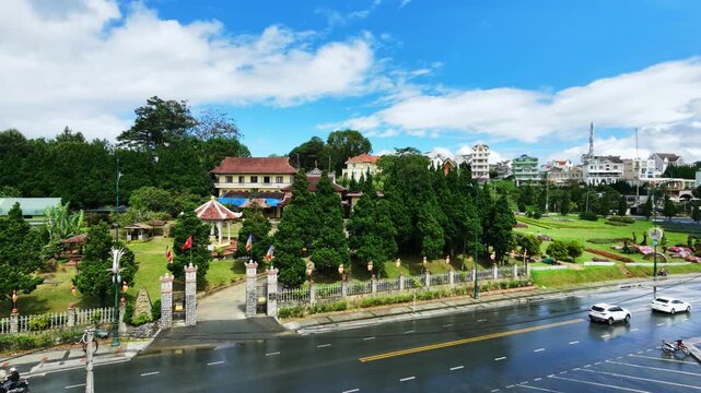 Panning shot of vehicles driving past lush garden park beside urban neighborhood in daylight