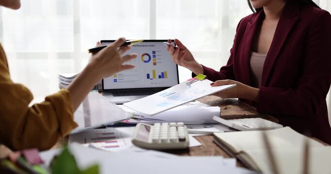 Businesswomen collaborating on financial data, analyzing reports and charts, planning investment strategies while working together in a professional office environment