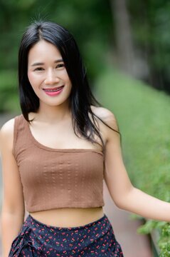 Young Woman Smiling Outdoors Surrounded by Lush Greenery in Nature