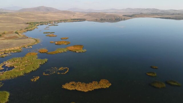 Lake in the mountains at sunset. Yellow autumn reeds on the lake. Aerial view. Beautiful autumn landscape.
