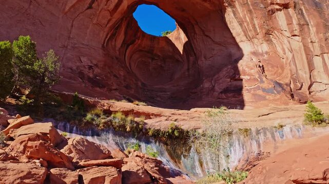 Warm evening light illuminates the dramatic pothole span of Bowtie Arch along the Bootlegger Canyon trail in Utah