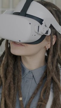 Slow motion of girl with dreadlocks having fun with virtual reality glasses using gaming device gesturing indoors. Entertainment and people concept.