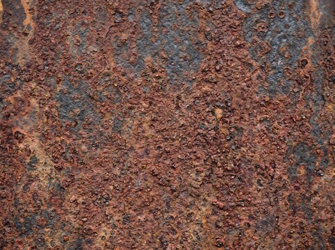 Rusted metal surface shows heavy corrosion with pitted orange and brown textures.