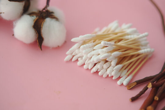 Assortment of cotton balls and cotton swabs displayed on a pink surface