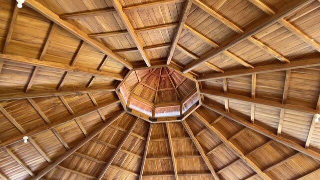 Wooden dome ceiling with intricate beams and central octagonal design. Natural wood tones highlight craftsmanship and warm textures. Perfect for rustic interiors or traditional architectural projects.