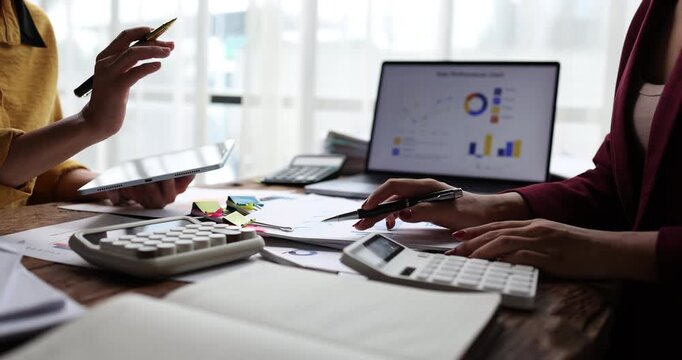 Businesswomen collaborating on financial data, analyzing reports and charts, planning investment strategies while working together in a professional office environment