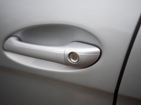 Close-up of a silver car door handle with integrated key lock, highlighting vehicle access, security and automotive design for repair, insurance and transportation concepts.
