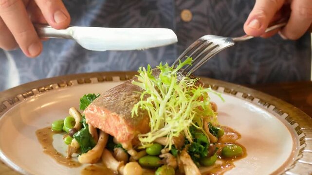 Grilled salmon fillet plated with edamame, mushrooms, and fris&eacute;e on white plate for restaurant menu presentation