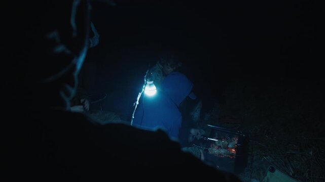 Group of men camping in the wild and gather near the bonfire and talk with each other. Fishermen camping and talk stories at night
