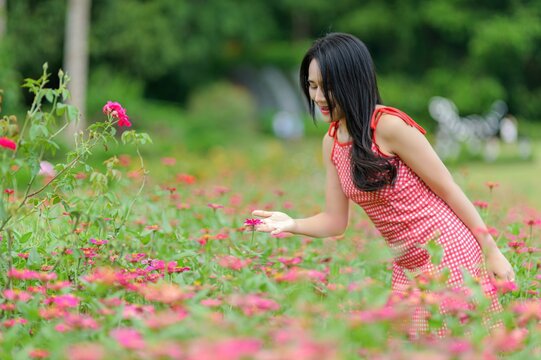 Woman in Red Dress Enjoying a Vibrant Flower Garden in Nature