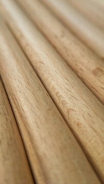 A steep angle view of several long wooden rods stacked parallel to each other. cylindrical timber dowels, raw woodworking materials, abstract minimalist textures.