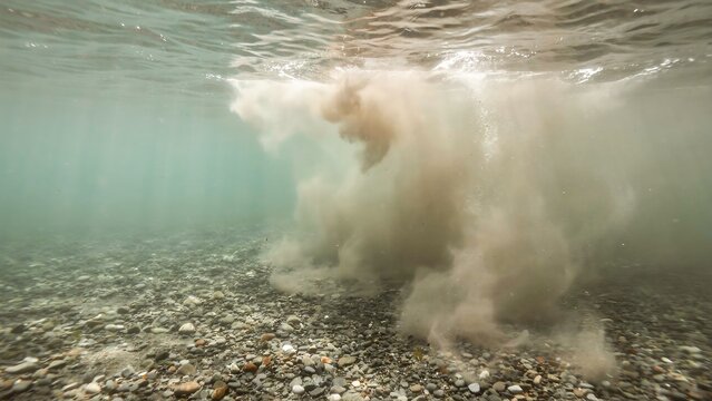 Underwater view of sediment cloud swirling over a rocky seabed
