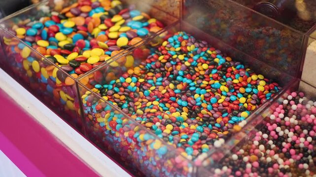 Different types of colorful candy in clear containers at a shop