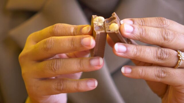Close up hands breaking chocolate bar with nuts revealing crunchy texture inside slow motion.