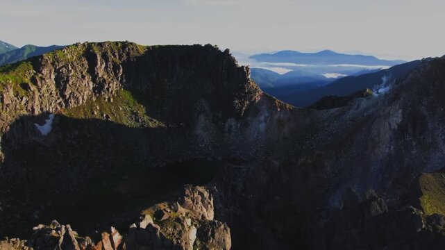 Cinematic view of a dramatic mountainside in Japan, showcasing rugged terrain, natural vegetation and beautiful mountainous scenery. Atmospheric Japanese wilderness and scenic countryside create a str