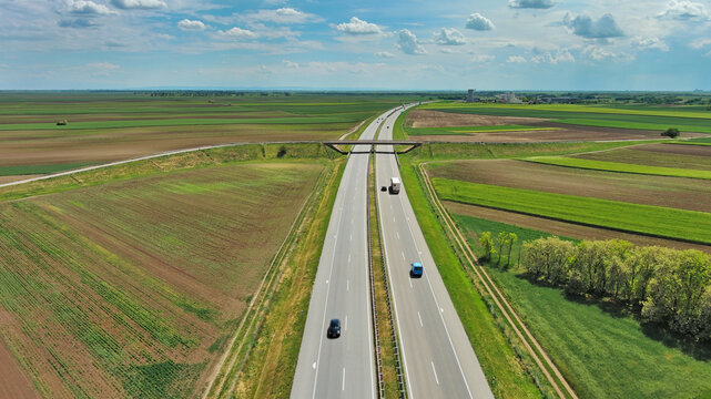 Aerial view of highway crossing green agricultural fields