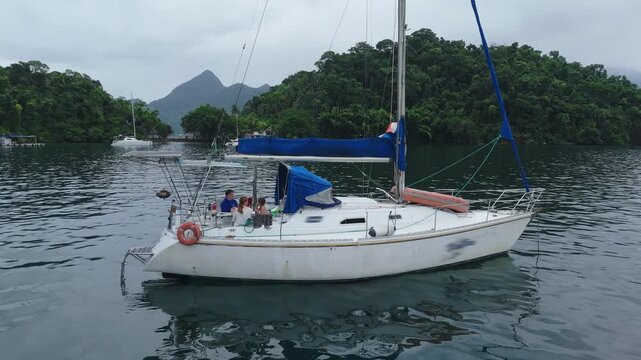 Sailing family. Sailing boat anchored in the tropical bay with family on board
