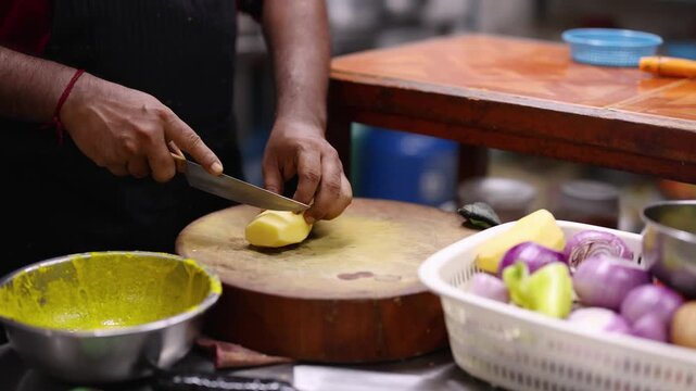 Chef Chopping Potatoes on Wooden Cutting Board in Kitchen