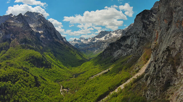 Rocky snow mountains and green valley aerial