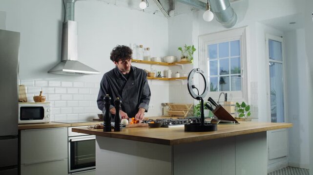Camera zooms out from a chef preparing food beside a ring light in kitchen