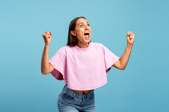 Young woman celebrating success with excitement and triumph isolated on blue background