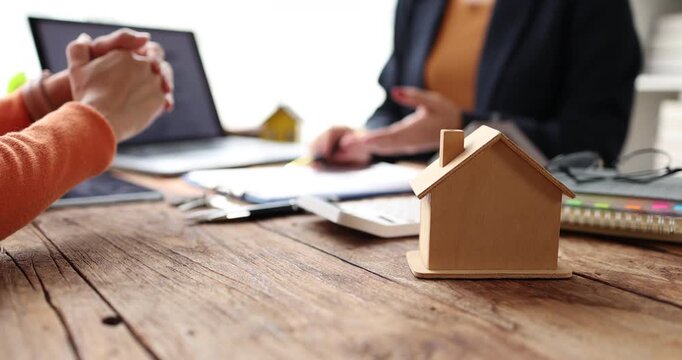 Real estate agent explaining housing loan mortgage details and investment options, holding a calculator and discussing contract agreement with a client buying a property