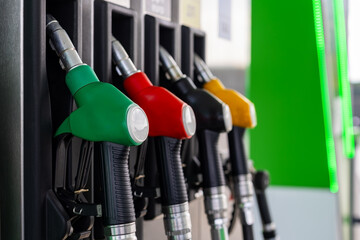 Colorful Fuel Pump Nozzles at Gas Station. Close-up of green, red, black and yellow fuel pump nozzles lined up in holders at a modern gas station. © Iryna