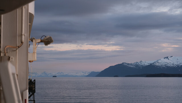 Breathtaking Alaska mountain glacier range view seen from outdoor deck of cruise ship liner sailing the Inside Passage transit with spectacular landscape scenery during sunset