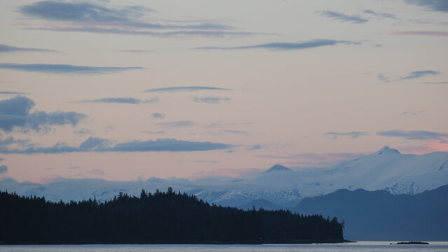 Breathtaking Alaska mountain glacier range view seen from outdoor deck of cruise ship liner sailing the Inside Passage transit with spectacular landscape scenery during sunset