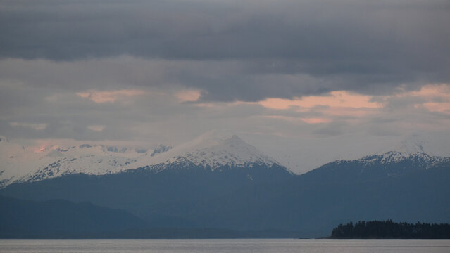 Breathtaking Alaska mountain glacier range view seen from outdoor deck of cruise ship liner sailing the Inside Passage transit with spectacular landscape scenery during sunset