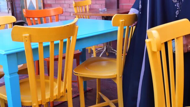Colorful vintage wooden chairs and tables at outdoor terrace cafe with sunlight in summer.