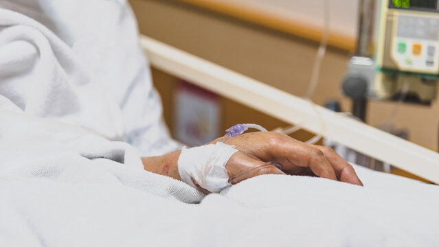 Closeup of patient hand resting hospital bed an intravenous line medical equipment showing healthcare treatment recovery inpatient care