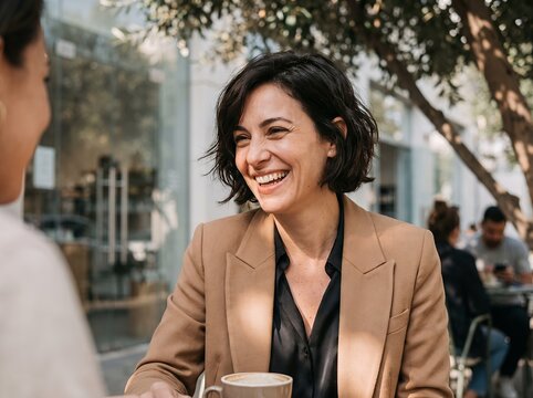 Cheerful Professional Woman Laughing at Outdoor Cafe Table with Friend, Happy Business Executive in Blazer Enjoying Coffee Break, Social Meeting Portrait