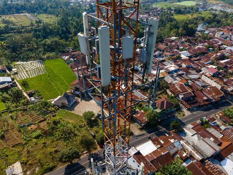 Multiple Radio Masts and Antenna Equipment on a Large Telecommunication Tower in a Rural Hilly Area Near a Populated Area in Indonesia. Communication Technology Viewed from Above.