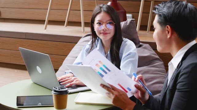 Asian Business Colleagues Discussing Reports in Modern Office Space