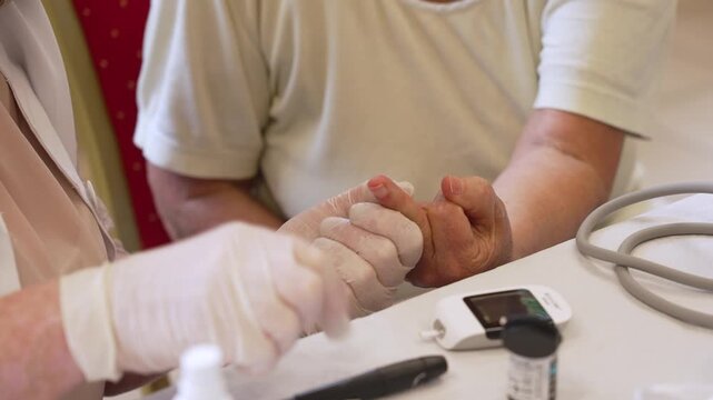 Medical professional performing a blood glucose test on a senior patient's finger in a clinic