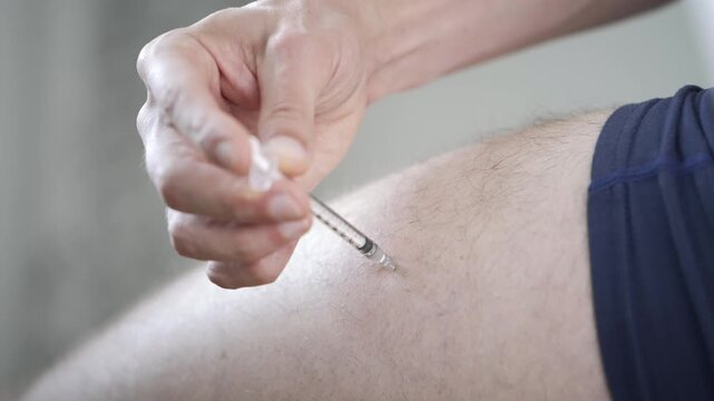 Man injects himself in the thigh pushing the last of the oil in before withdrawing the needle [TRT Concept]