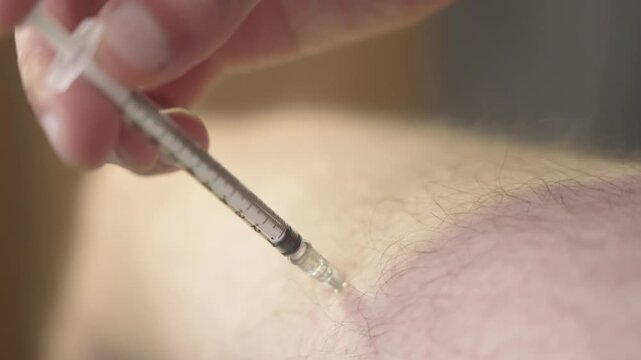 Close up of a needle drawn out of a thigh after the last of the dose is delivered leaving clean unmarked skin [TRT Concept]