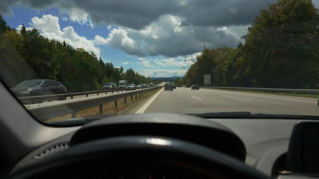German highway traffic seen from POV inside of car with steering wheel. Cars moving on Autobahn A8