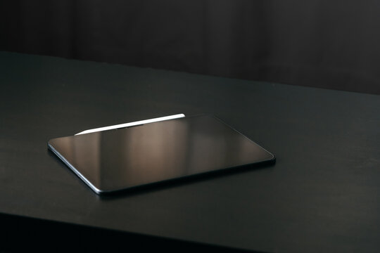 Laptop resting on a dark surface in a dimly lit room during the evening
