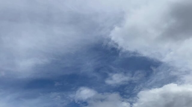Timelapse Overcast sky with dark grey and white clouds parting to reveal a patch of blue.