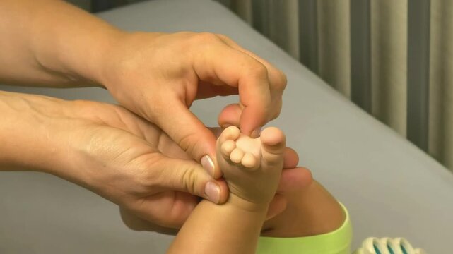 Adult hands gently tickle a baby's toes in close up at home, playful interaction, infant sensory development, family bonding and tender care.