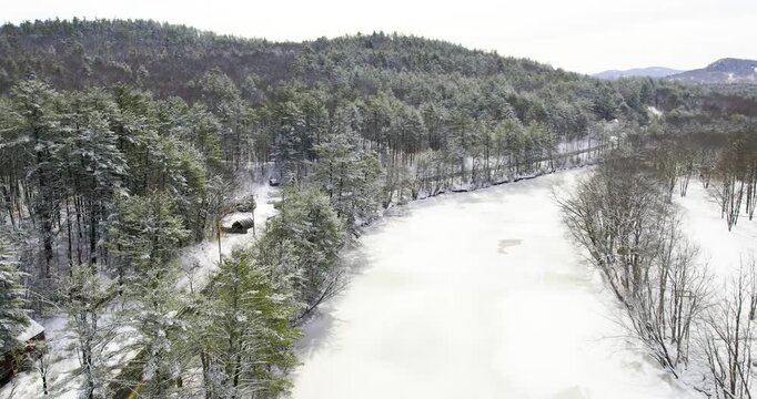 Drone flying over a snowy, frozen river and winding road in Maine.