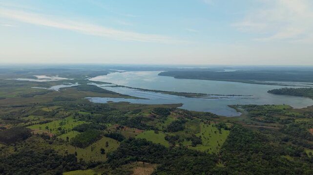 Paran&aacute; River wetlands and branching waterways surrounded by green pasture, woodland and rural farmland near Nueva Alborada, Itap&uacute;a, Paraguay, panoramic drone flyover