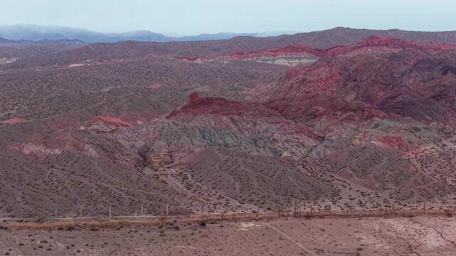 Red and gray eroded ridges of Sierra Colorada near Barreal, San Juan, Argentina, showing exposed sedimentary strata, arid scrub and deeply dissected terrain, parallax orbit shot